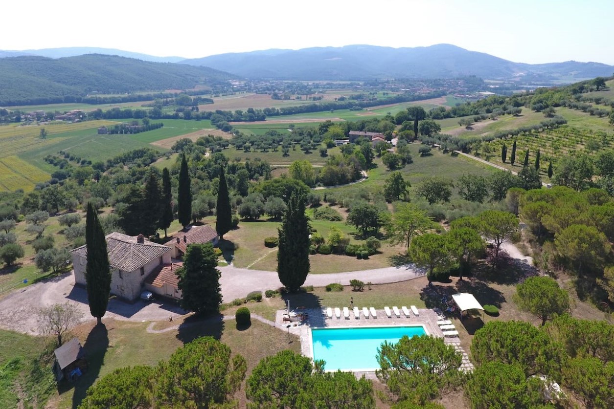 Stay Aerial view of the farmhouse with swimming pool among cypresses and olive trees