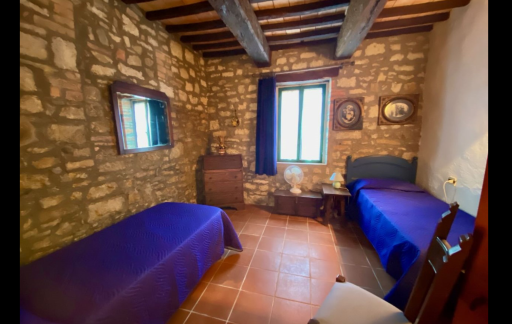 Bedroom with stone wall and two single beds in the Dolce Fede apartment