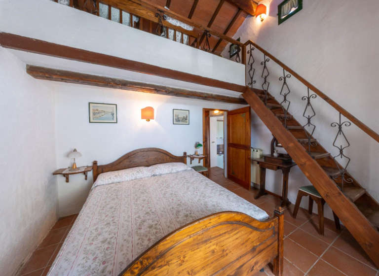 Bedroom with wooden staircase to the mezzanine in the Gaia apartment