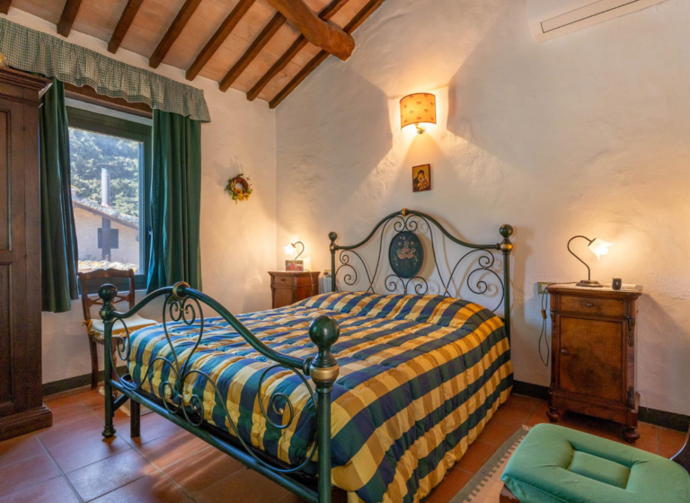 Bedroom with wrought-iron bed and wooden beamed ceiling in the Gran Marco apartment