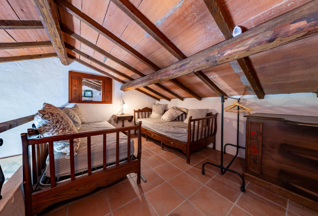 Bedroom under a sloping beamed ceiling in the Gaia apartment
