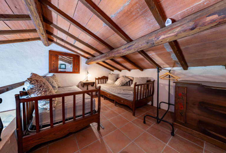 Bedroom under a sloping beamed ceiling in the Gaia apartment