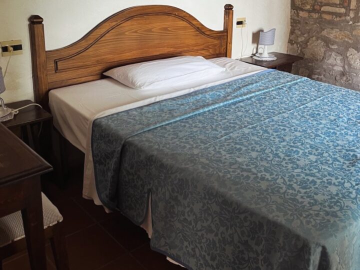Opgemaakt bed met blauwe sprei in een van de appartementen