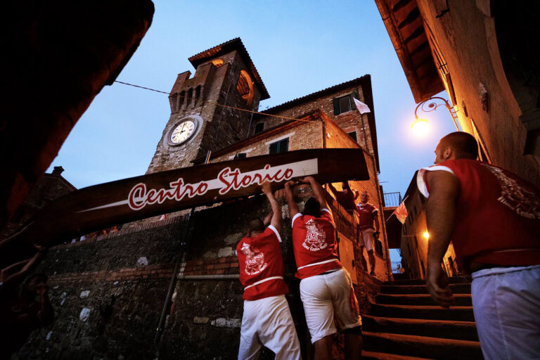 The Palio delle Barche procession marches on under the bell in Passignano sul Trasimeno