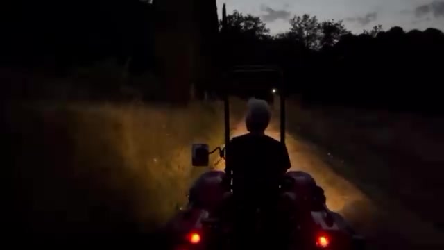 Op de tractor in de schemering, met de koplampen aan